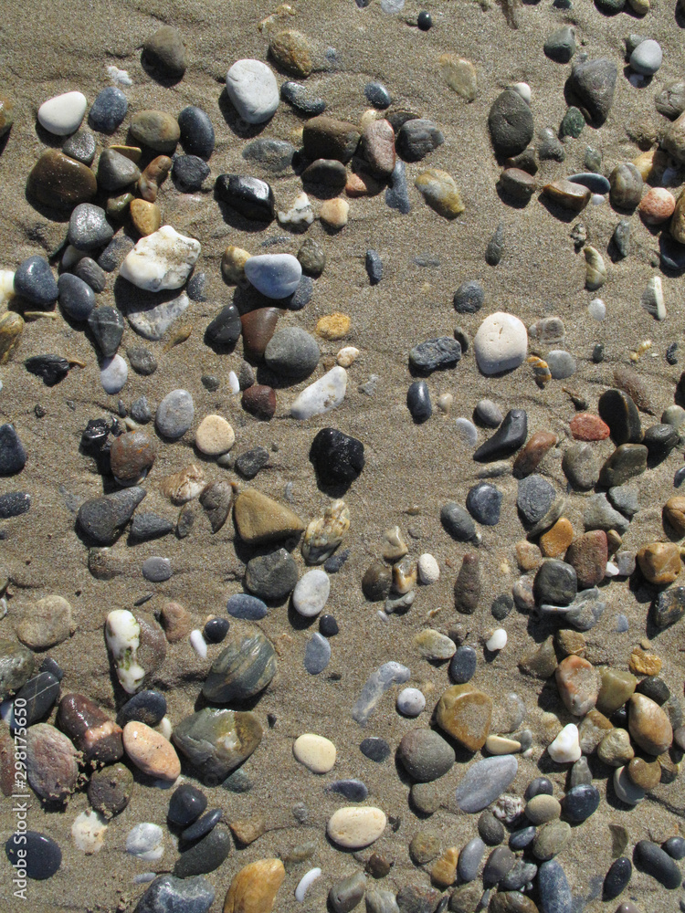 Wet different sea pebbles on the sandy beach Wet different sea pebbles on the sandy beach