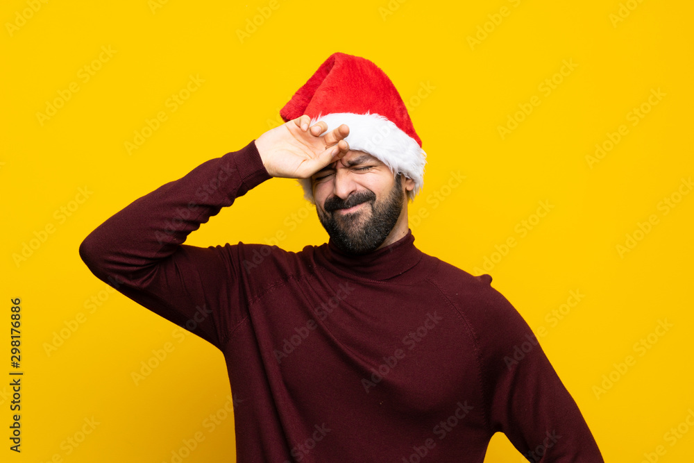 Man with christmas hat over isolated yellow background with tired and sick expression Man with christmas hat over isolated yellow background with tired and sick expression