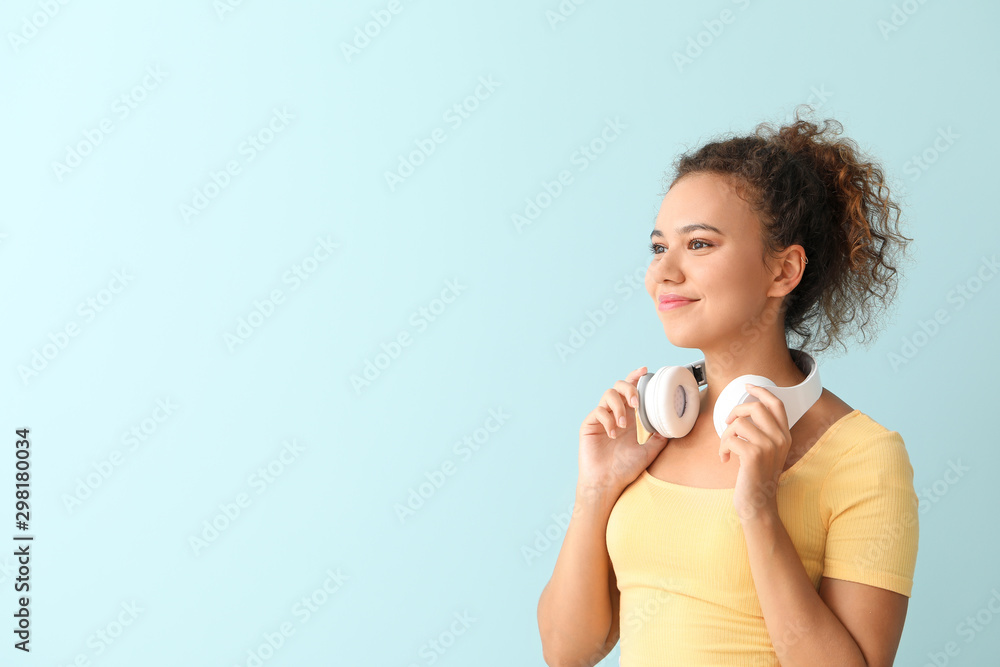 Beautiful African-American woman with headphones on color background Beautiful African-American woman with headphones on color background