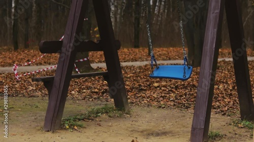 Empty swing in autumn park full of fallen leaves