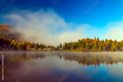 Lake fog panorama with autumn foliage and mountains with reflection.