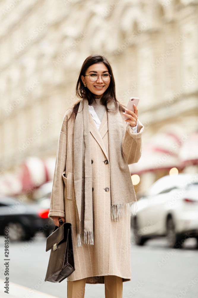A business lady of Asian appearance looks through applications on her smartphone in search of the nearest restaurant. Vertical frame A business lady of Asian appearance looks through applications on her smartphone in search of the nearest restaurant. Vertical frame