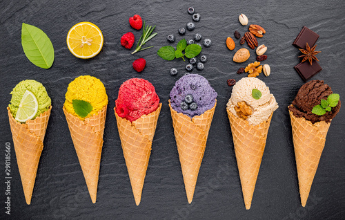 Various of ice cream flavor in cones blueberry ,lime ,pistachio ,almond ,orange ,chocolate ,vanilla and coffee set up on dark stone background . Summer and Sweet menu concept.
