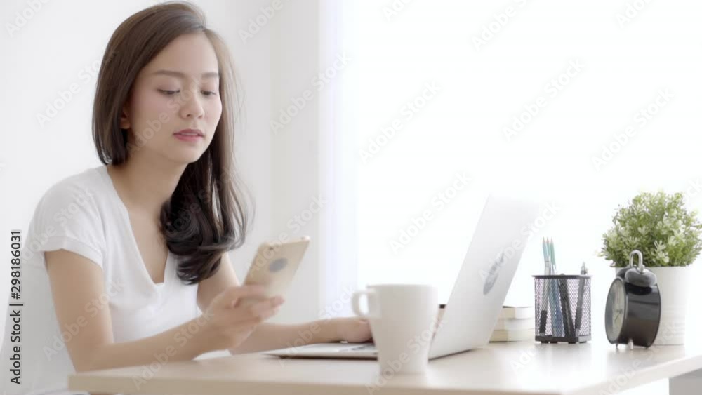 Beautiful young freelance asian woman smiling working on laptop computer and talking mobile smart phone at desk office with professional, girl using notebook, business and lifestyle concept. Beautiful young freelance asian woman smiling working on laptop computer and talking mobile smart phone at desk office with professional, girl using notebook, business and lifestyle concept.