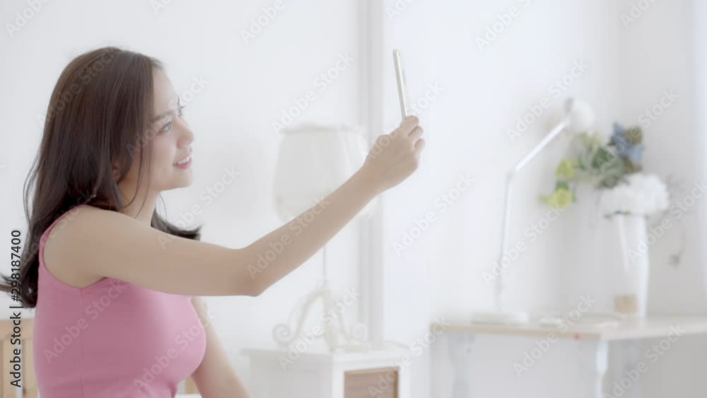 Beautiful portrait young asian woman sitting taking a selfie with smart mobile phone on bedroom in the morning at home, girl is photographing happy and smile with fun, lifestyle concept, slow motion. Beautiful portrait young asian woman sitting taking a selfie with smart mobile phone on bedroom in the morning at home, girl is photographing happy and smile with fun, lifestyle concept, slow motion.
