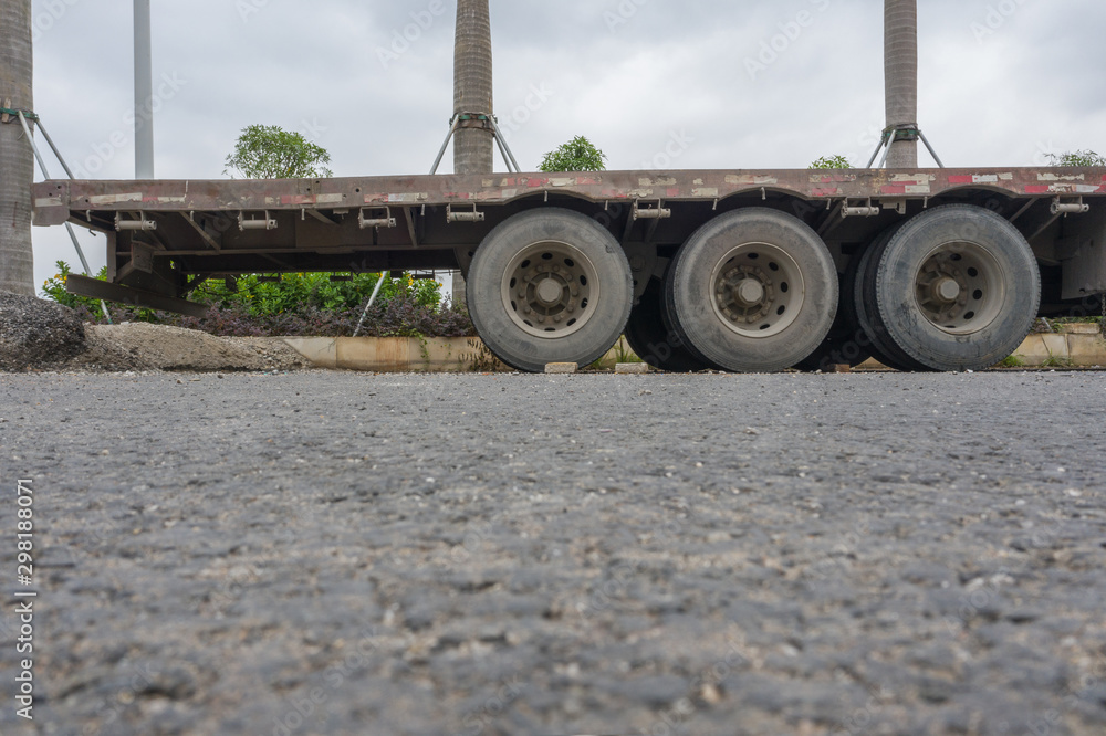A heavy-duty semi-trailer parked on an asphalt road, low angle view of the wheel close-up A heavy-duty semi-trailer parked on an asphalt road, low angle view of the wheel close-up
