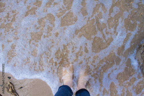 Sea washes feet. A wave on the shore. Relax on the beach. photo