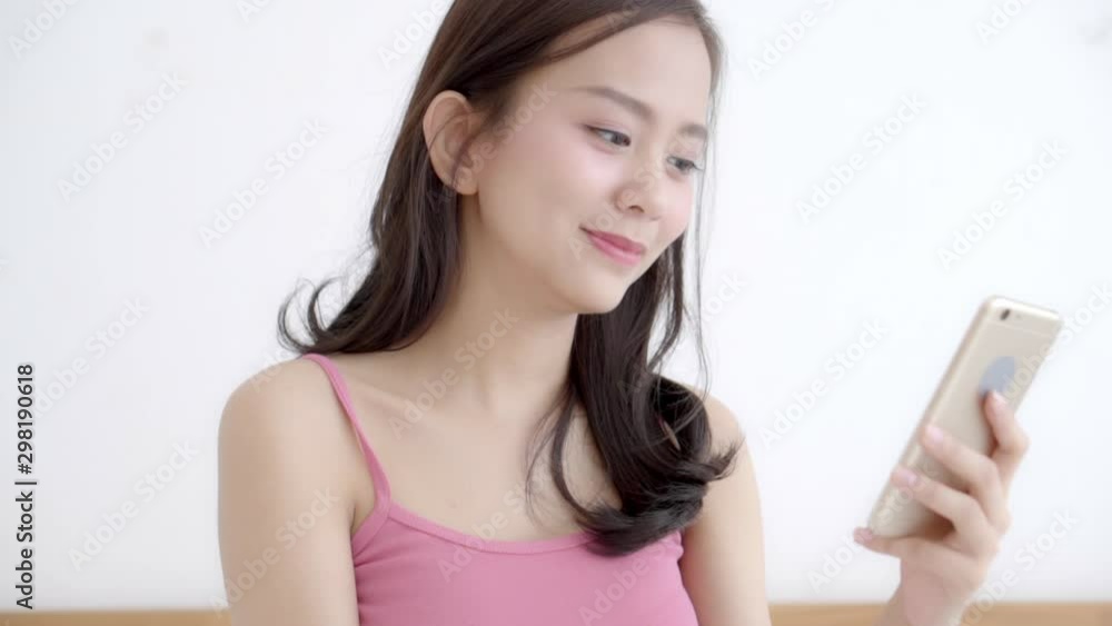 Beautiful portrait young asian woman smiling sitting look smart mobile phone reading social network with enjoy on bed at bedroom, girl chat messaging to internet online, communication concept. Beautiful portrait young asian woman smiling sitting look smart mobile phone reading social network with enjoy on bed at bedroom, girl chat messaging to internet online, communication concept.