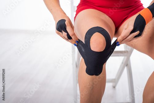 The athlete puts a medical tape on his knee. alternative treatment for joint and tendon injuries. Physiotherapy of chronic inflammation of the joints of the female leg.