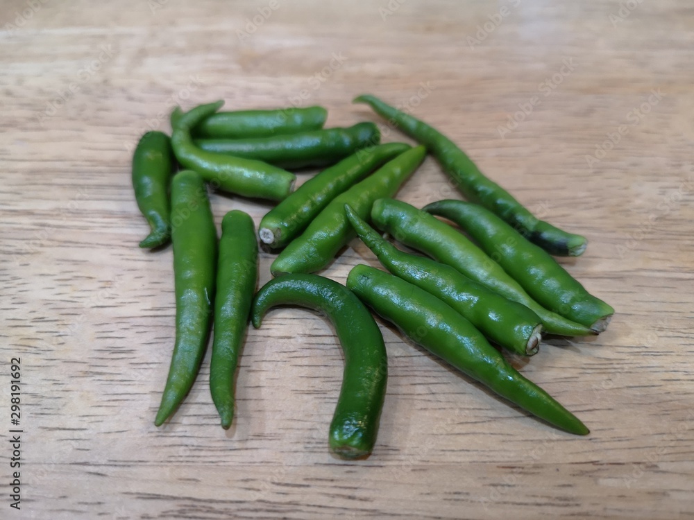 Spicy green peppers, isolated on a wooden floor Spicy green peppers, isolated on a wooden floor