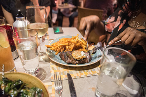 a close up of steak and fries dinner on a table at a restaurant in warm tone lighting