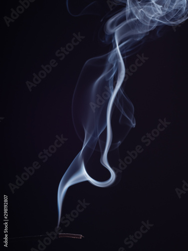 Steam of swirling white smoke, isolated on black background, close up view. Abstract background of burning incense, brush effect. Eastern fragrance for meditation and relaxation