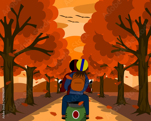 Lovers riding motorcycles. Thay travel together on a small, beautiful road surrounded by nature. On both sides there are trees with orange leaves. Orange sky at sunset.