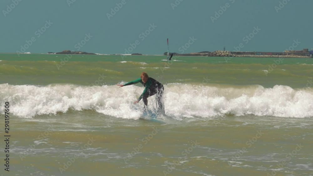 Beginner surfer girl falling off surfboard into waves, Morocco, Essaoiura Beginner surfer girl falling off surfboard into waves, Morocco, Essaoiura