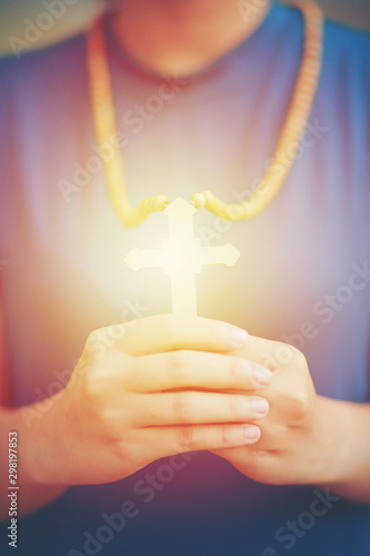 Close-up wooden cross in the hand with focus on the cross blessing from god on sunlight background, hope concept.