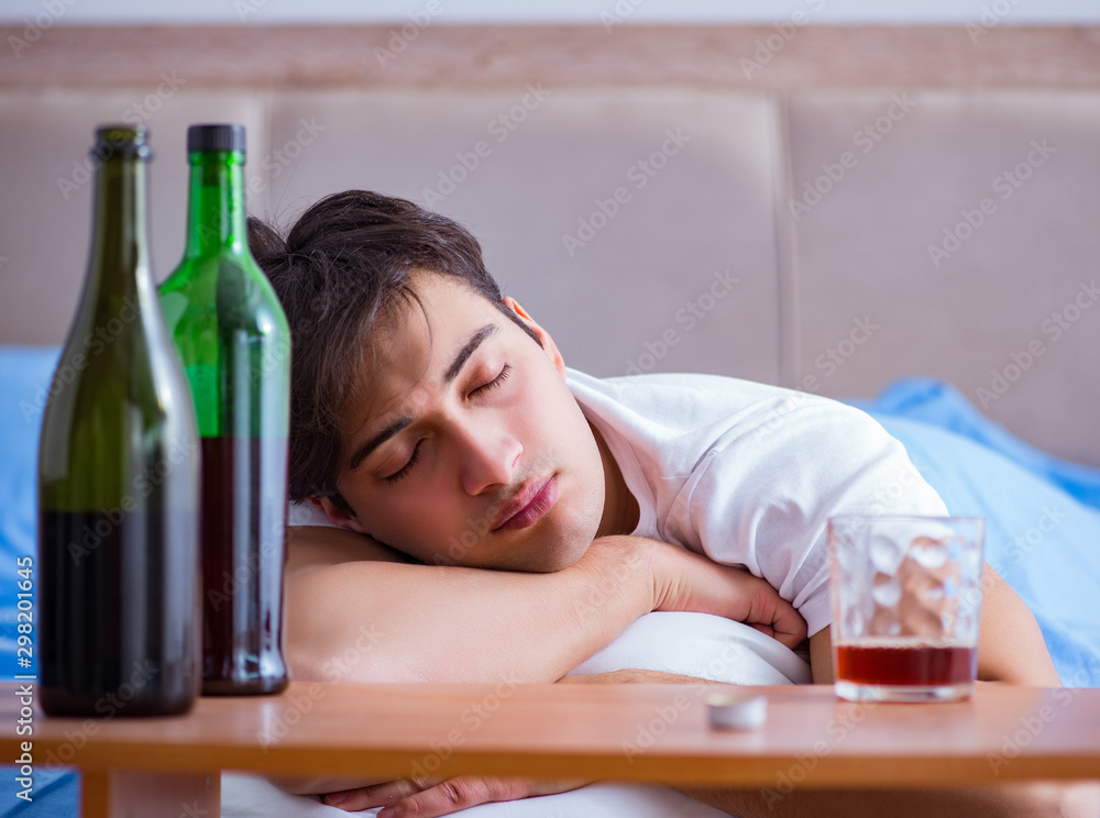 Man alcoholic drinking in bed going through break up depression Man alcoholic drinking in bed going through break up depression
