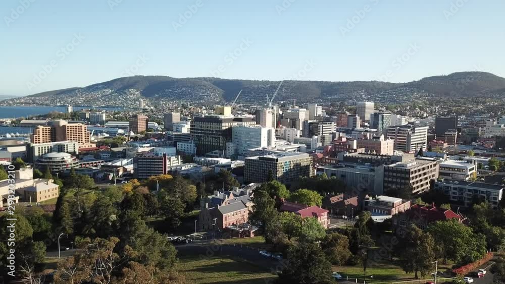 Aerial drone pan around over medium scale city during golden hour with mountains in background, Hobart, Tasmania. Aerial drone pan around over medium scale city during golden hour with mountains in background, Hobart, Tasmania.