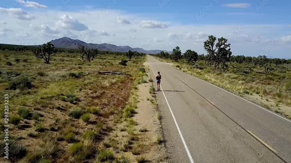Aerial View of Woman Walking Down Wilderness Road Surrounded By A Joshua Tree Forest Aerial View of Woman Walking Down Wilderness Road Surrounded By A Joshua Tree Forest