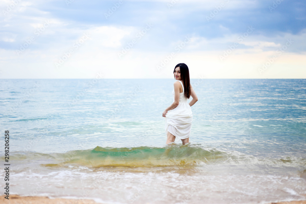 Beautiful girl young woman asia standing in water on sandy on the beach at sunset,enjoy summer vacation on the beach.