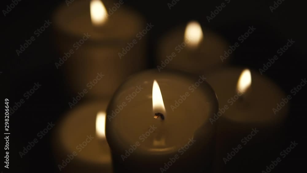 Static shot of group four lighted candle, composition on black background, slow motion Static shot of group four lighted candle, composition on black background, slow motion