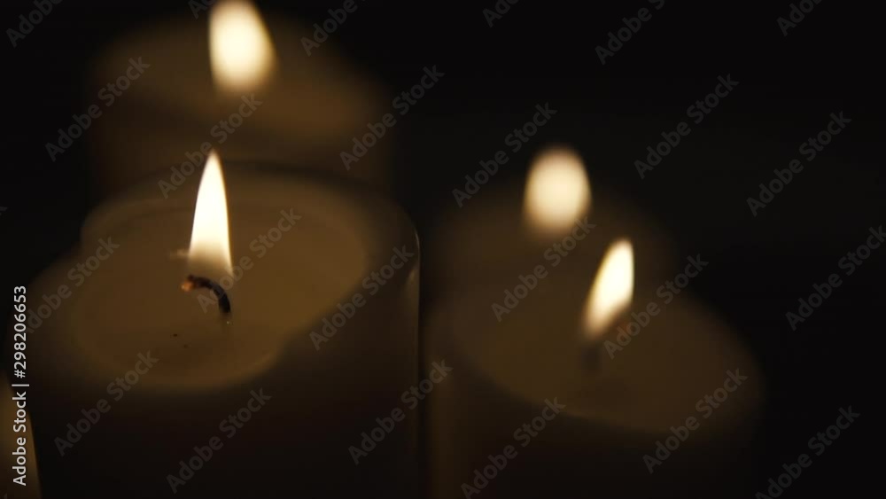 Slow movement over burning candles, composition on black background, candles of different sizes stand side by side, slow motion Slow movement over burning candles, composition on black background, candles of different sizes stand side by side, slow motion