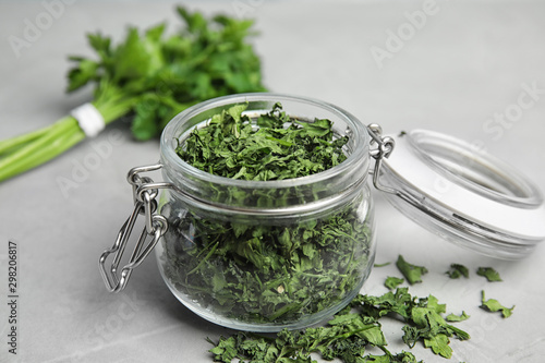 Glass jar with dried parsley on grey stone table