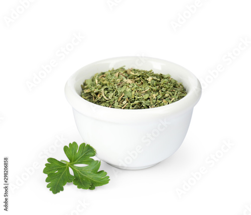 Bowl with dried parsley and fresh twig on white background