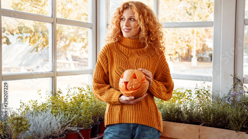 Foto Woman holding carved pumpkin, preparing halloween celebration at home