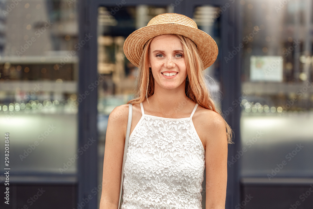 Traveler. Young woman in hat standing on street smiling cheerful