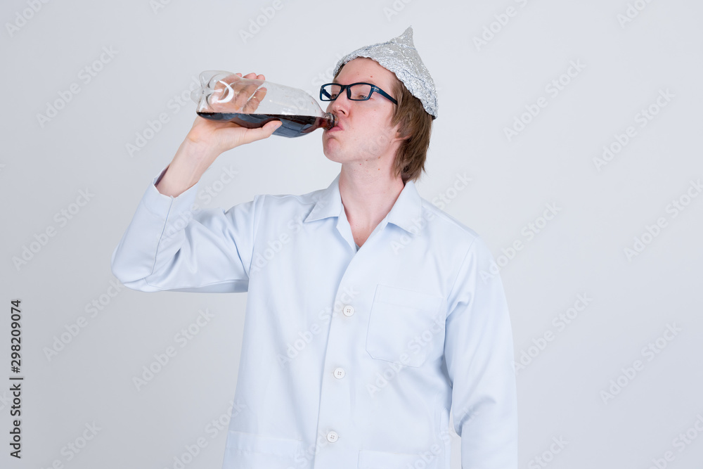 Young man doctor with tinfoil hat drinking bottle of soda Young man doctor with tinfoil hat drinking bottle of soda