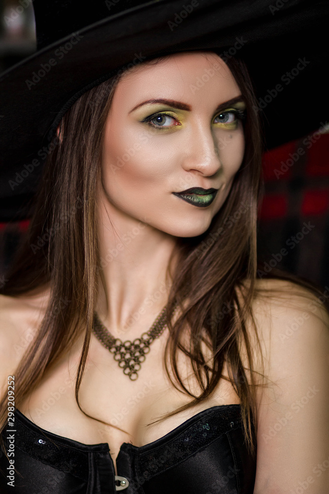 Portrait of a beautiful, young witch with a green make-up in a black pointed hat. Studio photo, model with clean skin, Halloween. Portrait of a beautiful, young witch with a green make-up in a black pointed hat. Studio photo, model with clean skin, Halloween.