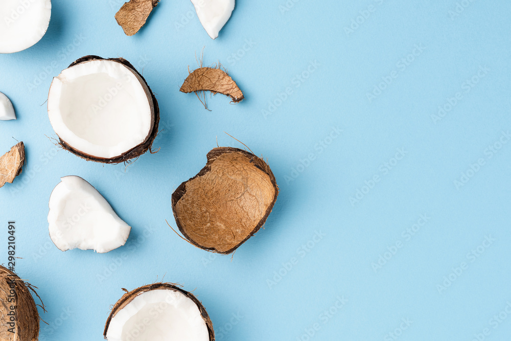Fototapeta premium Fresh cracked coconut on blue background with copyspace. Flat lay