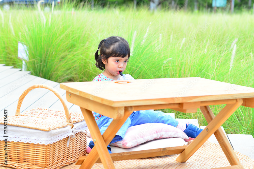 Little Child Girl Drinking Water on The Table with Grass Flower