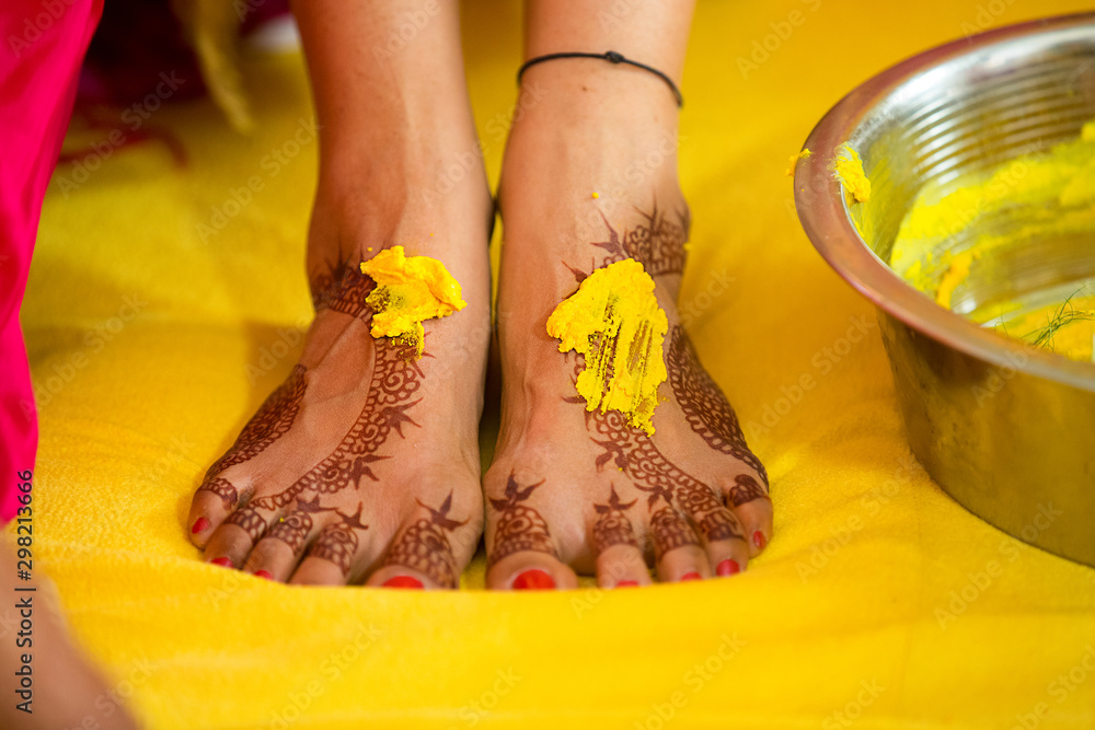 Closeup of Indian bridal haldi and mehndi henna foot, pasting turmeric