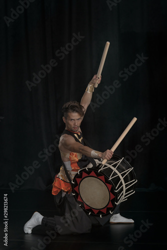 Full length portrait of a Japanese drummer Taiko on a dark stage.