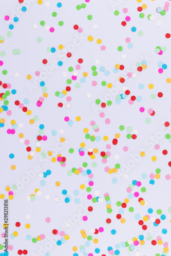 A pattern of multicolored shiny confetti scattered randomly on white background