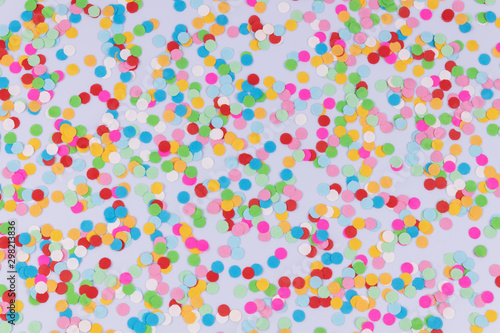 A pattern of colorful bright round multicolored confetti scattered on white background