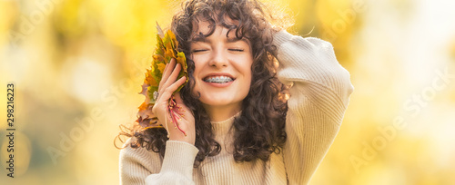 Young woman full of emotions from autumn season. Girl with a dental braces and curly hair