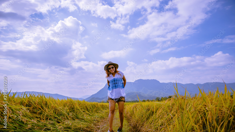 Asian women travel Rice fields Golden yellow On the mountains in the holiday. happy and enjoying a beautiful nature. travelling in countrysde, Green rice fields, Travel Thailand. Asian women travel Rice fields Golden yellow On the mountains in the holiday. happy and enjoying a beautiful nature. travelling in countrysde, Green rice fields, Travel Thailand.