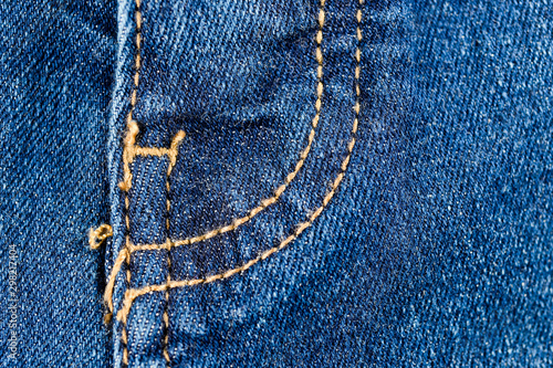 Close-up texture of blue denim stitched with orange thread