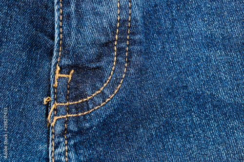 Close-up texture of blue denim stitched with orange thread