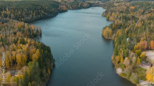 Aerial, tilt up, drone shot, over lake Nuuksion Pitkajarvi, surrounde by colorful, autumn color forest, in Nuuksio national park, on a partly sunny, fall day, in Espoo, Uusimaa, Finland photo