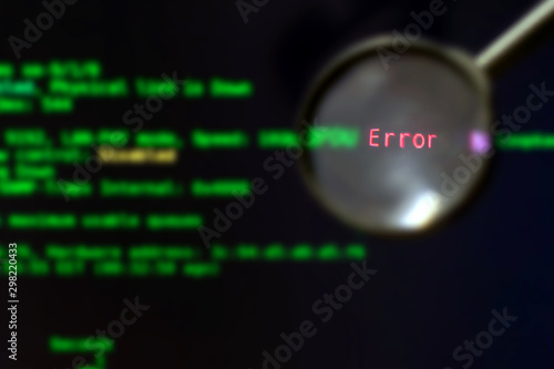 The magnifier is on a black background with green blurred text, selective focus. Software testing. The concept of finding errors in computer programs