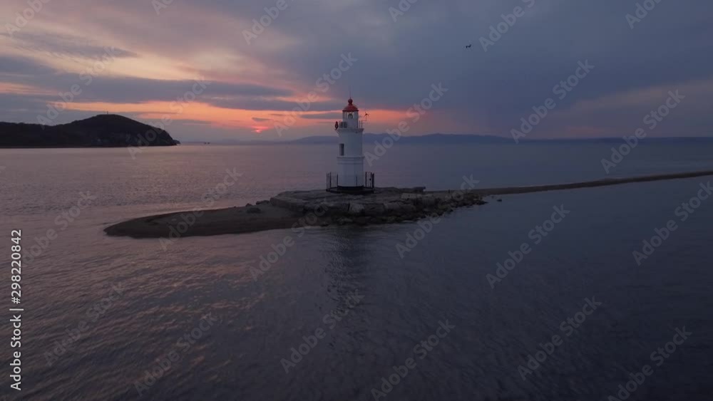 Beautiful lighthouse on sand bar. Romantic purple sunset clouds Seagulls fly by Calm ocean sea. Russia Vladivostok sight Asia. Navigation happiness peace of mind. Aerial Drone Beautiful lighthouse on sand bar. Romantic purple sunset clouds Seagulls fly by Calm ocean sea. Russia Vladivostok sight Asia. Navigation happiness peace of mind. Aerial Drone