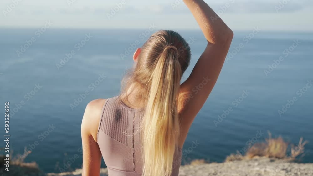 Backside view of woman practices yoga on mat, meditates at morning, slow motion Backside view of woman practices yoga on mat, meditates at morning, slow motion