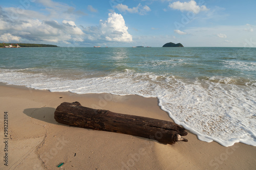 a beached timber with islands background at Samila Beach, Songkhla, Thailand.