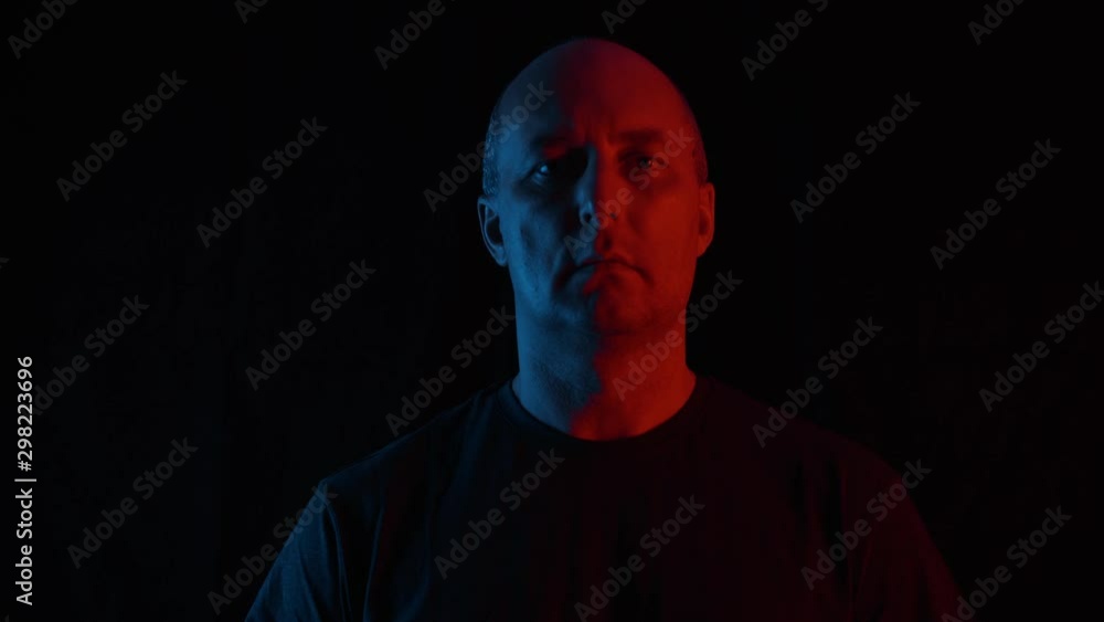 Portrait of serious middle aged man looking at camera in darkness. Handsome confident bald mature man looking down and looking at camera on black background Portrait of serious middle aged man looking at camera in darkness. Handsome confident bald mature man looking down and looking at camera on black background