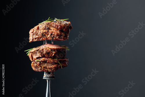 Fotografia Grilled ribeye beef steak with rosemary on a black background.