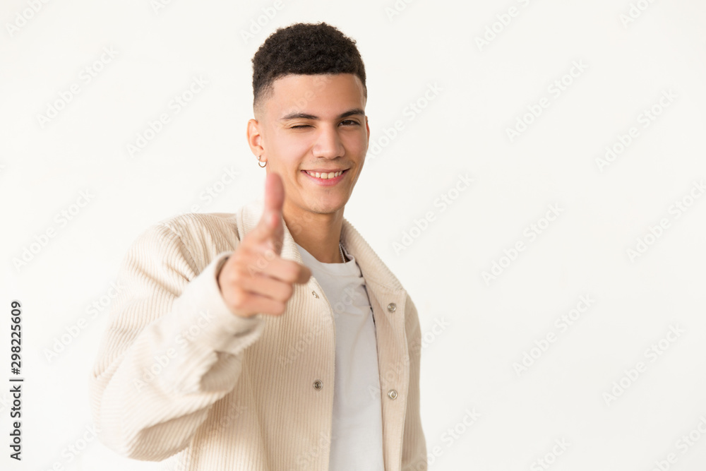 Smiling man winking at camera. Portrait of cheerful handsome young man winking, pointing with finger and smiling at camera. Gesture concept Smiling man winking at camera. Portrait of cheerful handsome young man winking, pointing with finger and smiling at camera. Gesture concept
