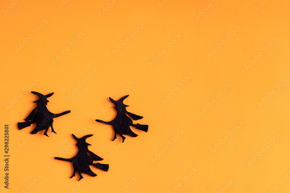 Three black witches on orange background. Minimal flat lay. Halloween